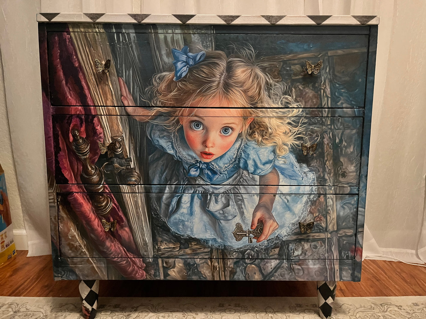 Furniture piece with a painted design of a young girl in a blue dress.