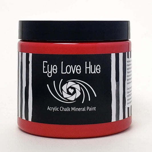 A red jar of Eye Love Hue acrylic mineral paint with a black label featuring white stripes and an eye graphic design.